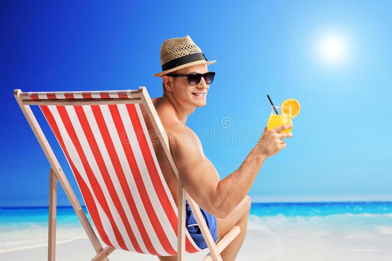 Flierefluiter  met drankje in een strandstoel op een zonnig strand 